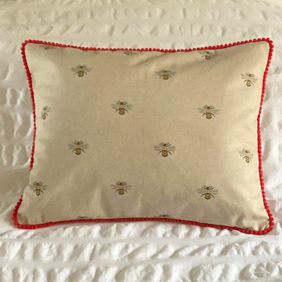 bees cushion on bed with red trim