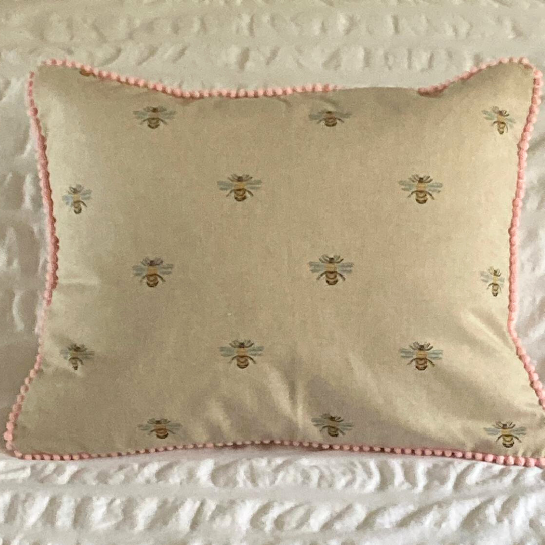 bees cushion on bed with pink trim