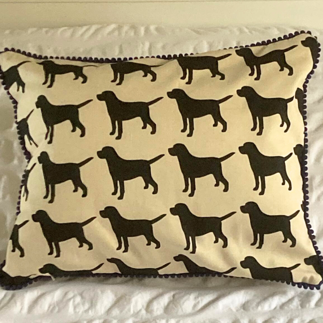 black labrador cushion in navy trim on bed