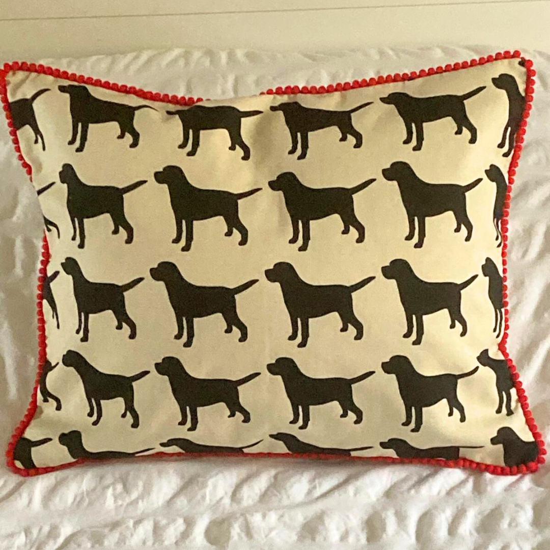 black labrador cushion in red trim on bed