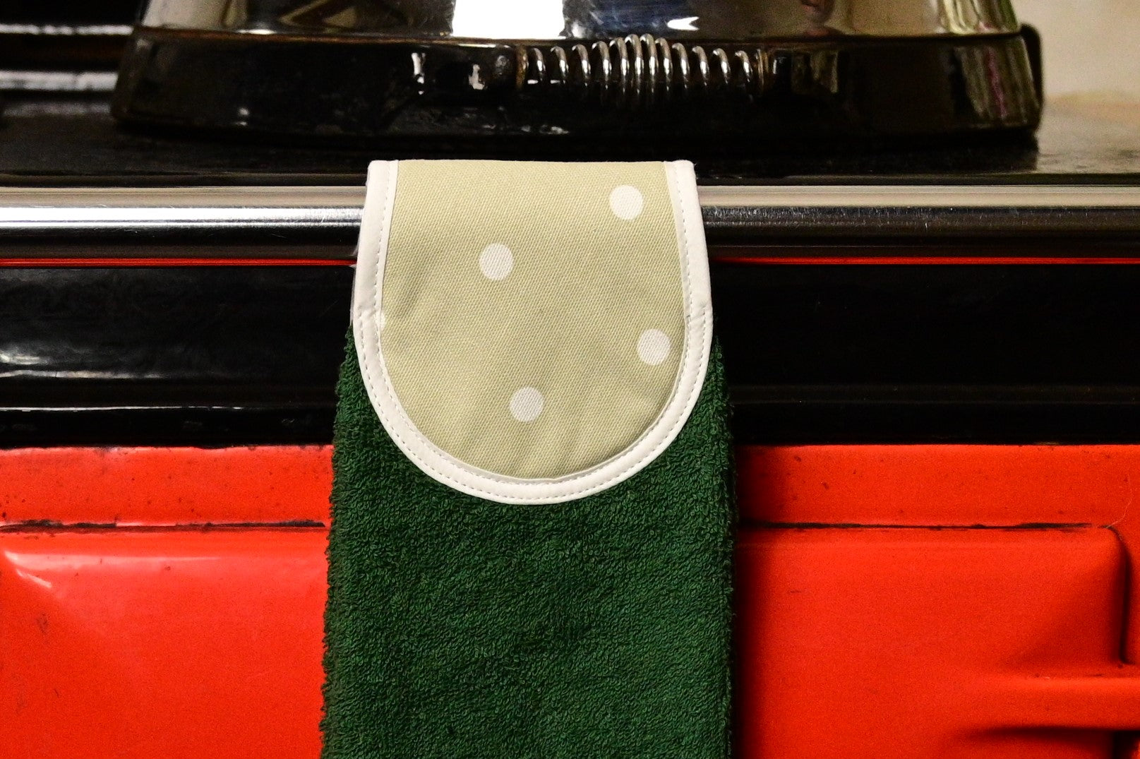 green spots hang up towel on red aga rail close up