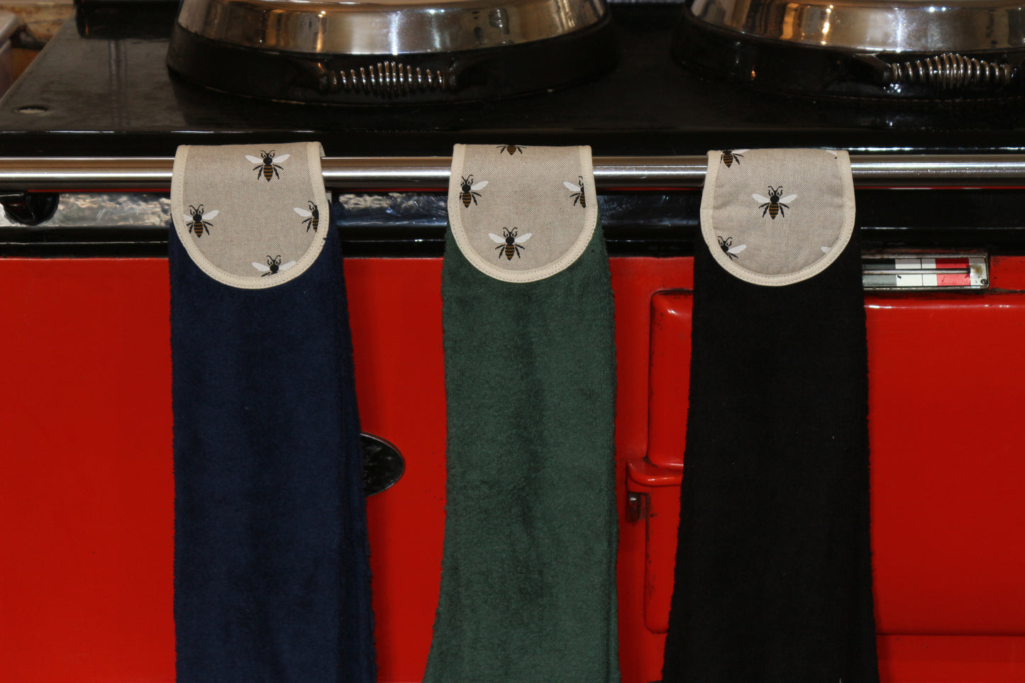 navy, green and black old bees design hang ups on red aga rail