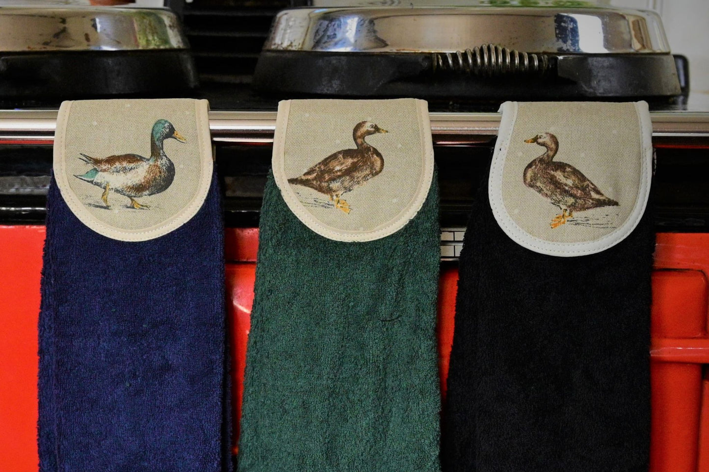 navy, green and black hang ups in mallard ducks on red aga rail close up