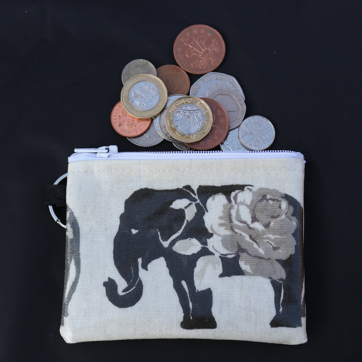 A grey elephant patterned waterproof zipped small mini wallet with a coin purse on top and a ring attachment on the side, displaying various coins and bills.